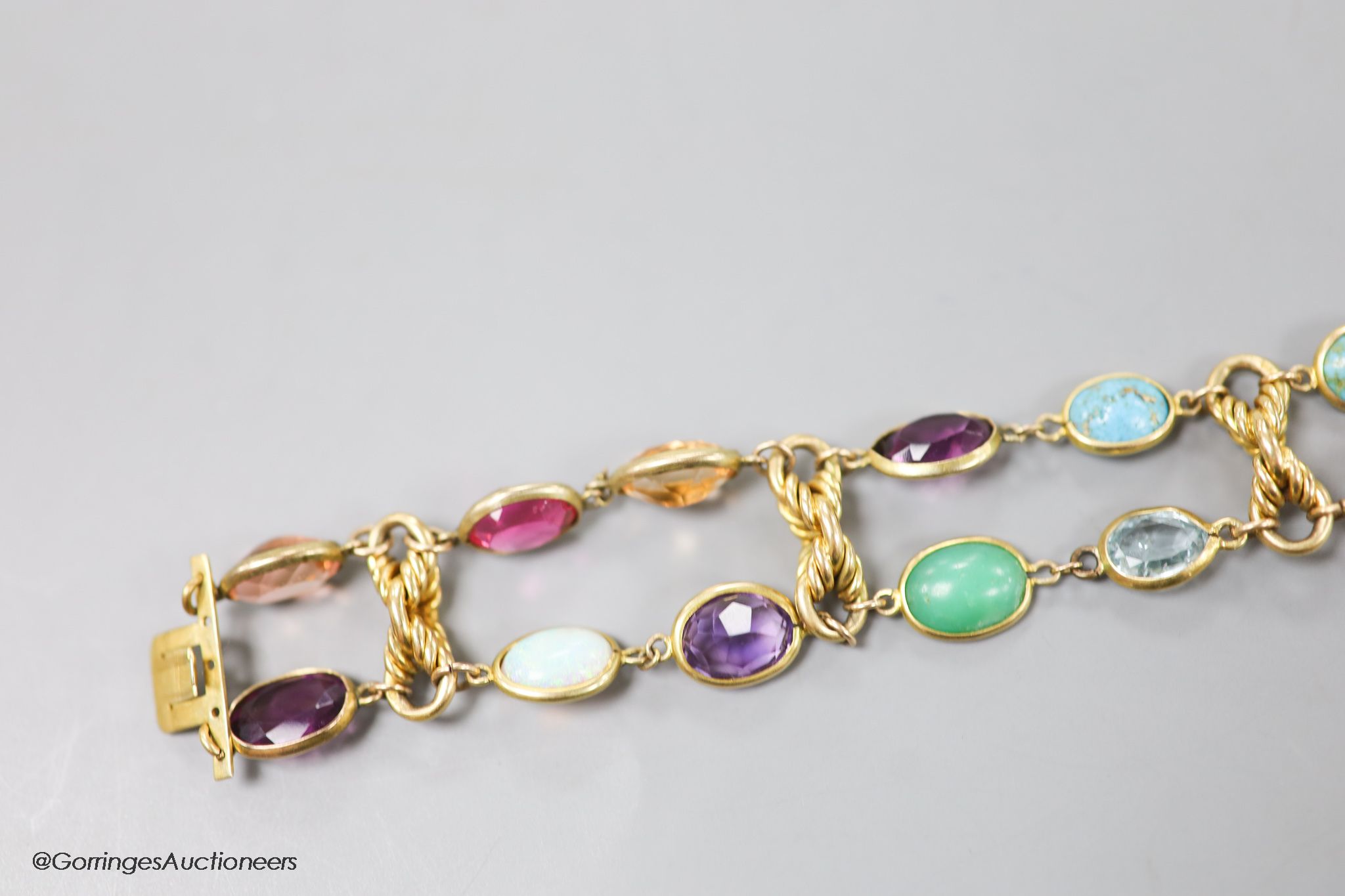 An early 20th century yellow metal and multi gem set bracelet, including white opal, turquoise, amethyst etc, 17cm, gross weight 30.3 grams.
